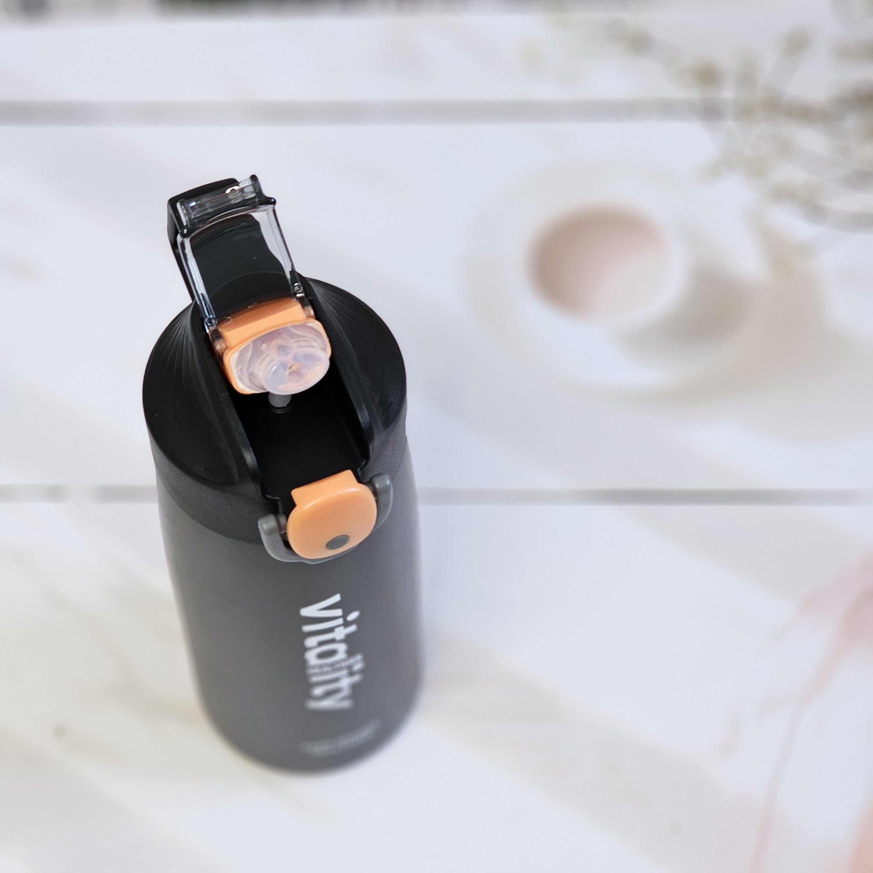 Insulated water bottles for hot and cold drinks, in black, white, and pink, with a flip-top lid and 'vitality' branding. www.usmile.toys